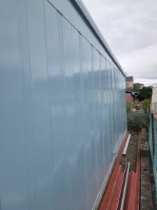甲斐市K様邸 倉庫の施工後シャッター面。外壁と統一した世田谷ベース色で清潔感ある仕上がり。